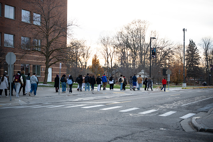 A large group of people walk down a sidewalk in front of CMU's Park Library