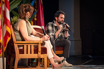 Actor Penn Badgley and psychotherapist Nura Mowzoon sit in chairs on a stage speaking to the audience