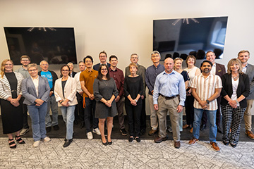 A group of people standing in a room together and smiling.