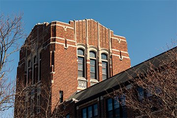 Sunshine hits a tall brick building with many windows.