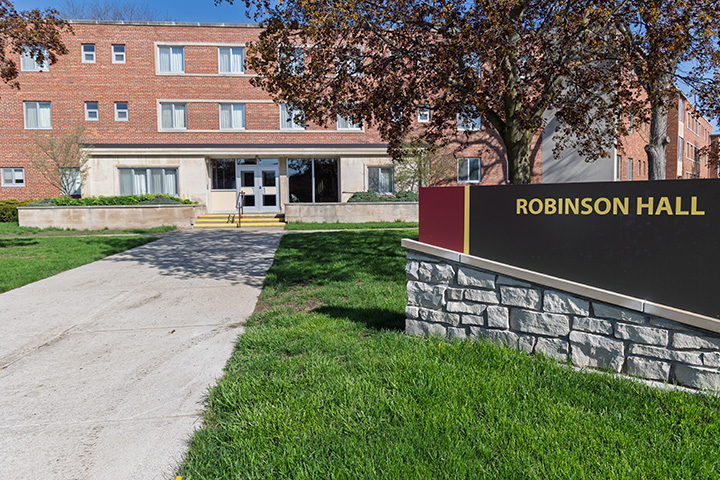 In the foreground, a sign reads Robinson Hall. In the background, a brick building.
