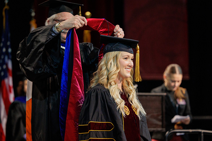 A woman wearing a graduation cap and gown.
