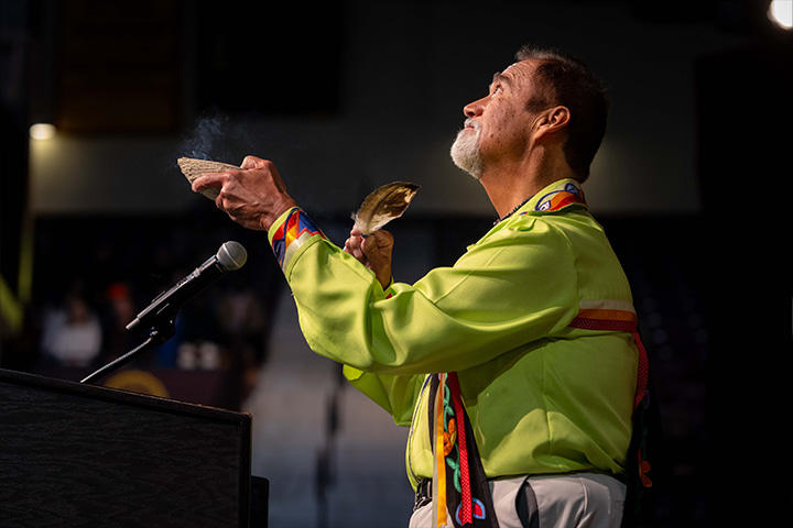 A man holding a smoking herbs and standing in front of a microphone.