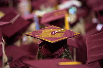 A photo of a maroon graduation cap with a gold Action C worn by a graduate at CMU commencemen