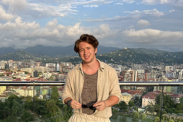 A man standing on a balcony with a city in the background