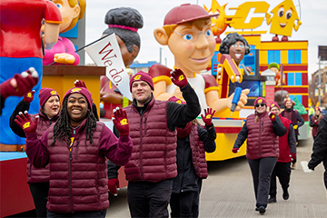 A group of people wearing vests walking in a parade.