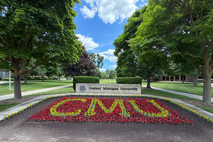 Flowers spelling the letters CMU in front of a Central Michigan University sign