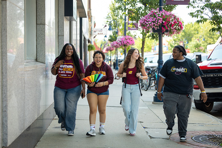 Four college students wearing CMU clothing walk down a sidewalk