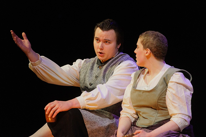 A man and woman sitting on a stage acting in a play.