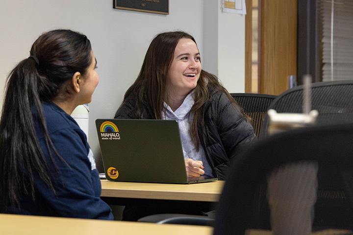 Two female students sitting at a table with a laptop