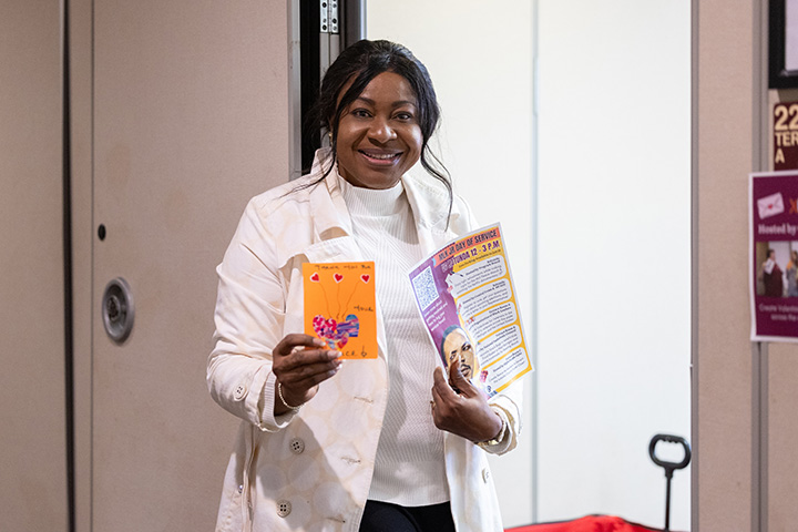 A woman dressed in white holding a handmade card and flyer