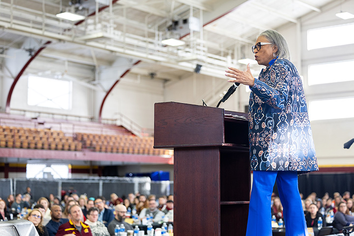 A woman standing at a podium with a crowd in the background