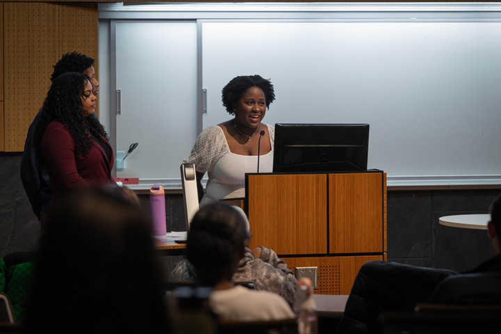 A woman standing at a podium with a whiteboard behind her