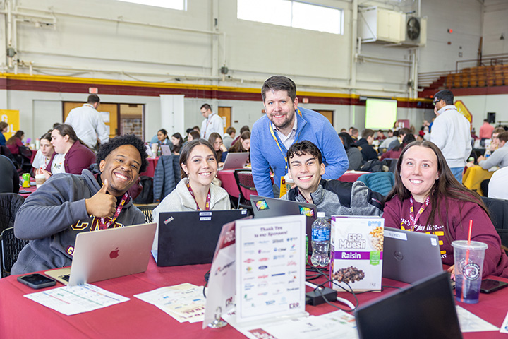 A group of people sitting at a table with laptops inside Finch Fieldhouse