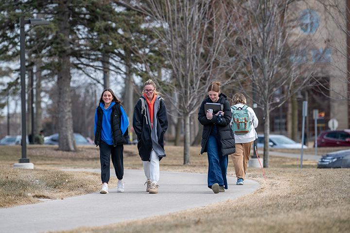 A group of female students walking on a sidewalk through CMU's campus