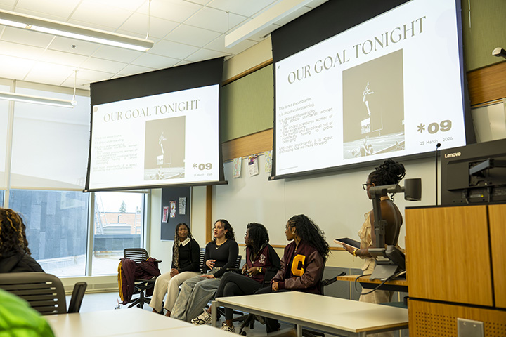 Four female CMU student athletes sit at the front of a classroom giving a panel discussion