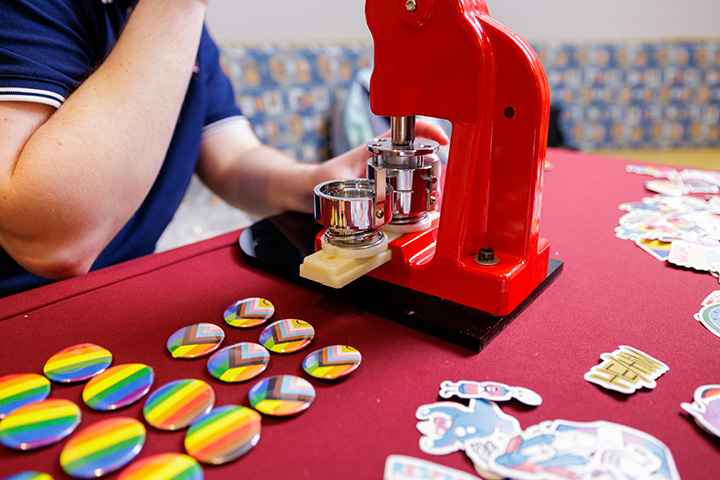 A closeup of a person using a button-maker machine