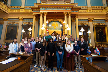 A group of students pose for a photo inside the Michigan State Capitol Building