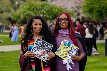 Mother and daughter graduates Sheena and Alondra pose for a photo while holding their personalized graduation caps