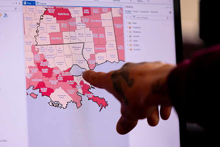 A hand pointing at a map of Louisiana