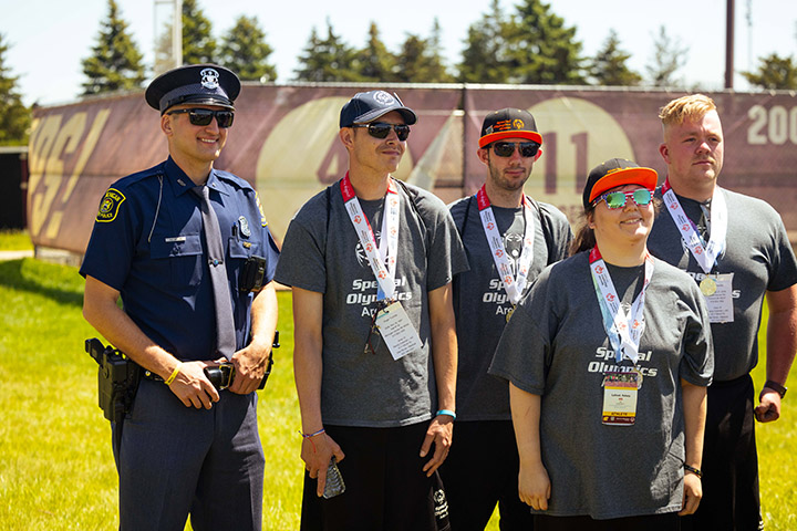A police officer poses for a photo with four Special Olympics athletes
