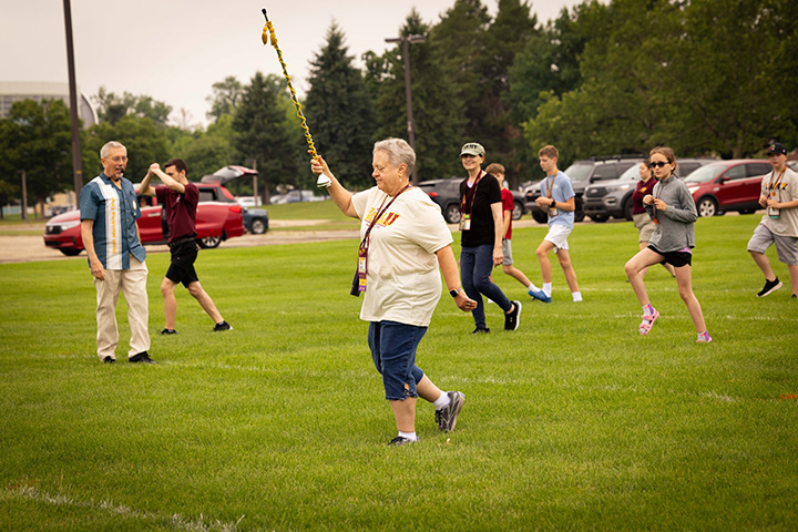 Grandparents and grandchildren march across a field like members of a marching band