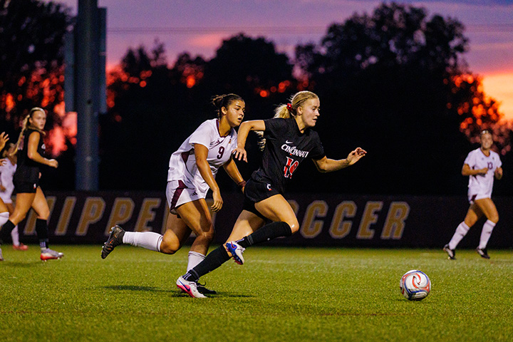 CMU soccer players run down the pitch with a beautiful sunset in the background