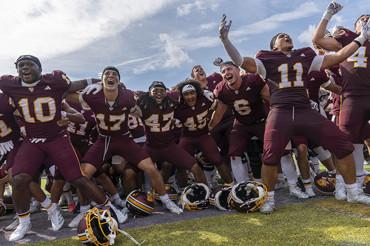A low-angle photo of CMU football players celebrating a victory