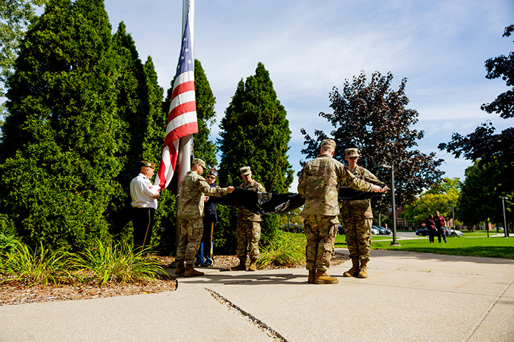 ROTC members fold a flag in front of a flag pole on CMU's campus