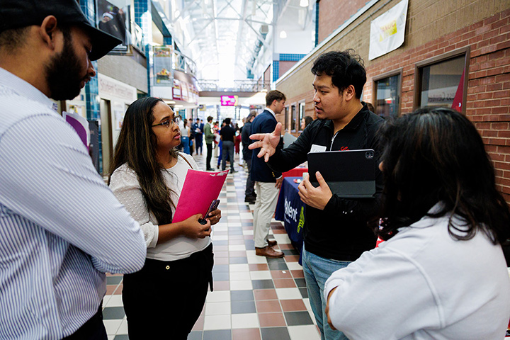 Four STEM students talk in a large hallway during a STEM Career Fair