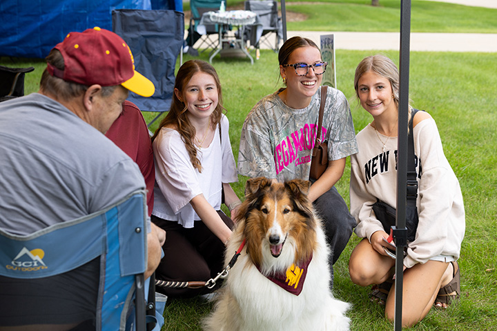 Three female students pose with a collie dog