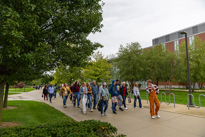 A group of students and parents walk down the sidewalk through CMU's campus