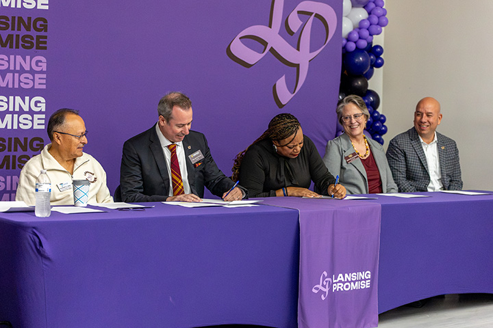 President MacKinnon and four others at a signing event for the Lansing Promise