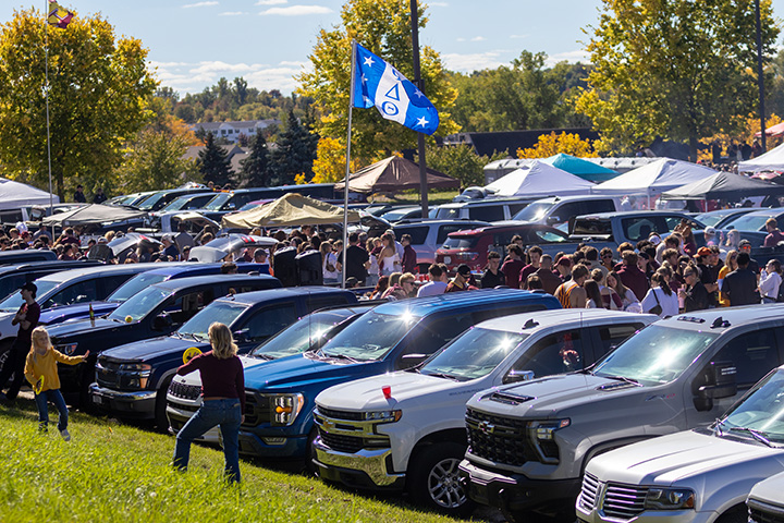 A wide angle view of vehicles and tailgaters in a parking lot prior to a football game