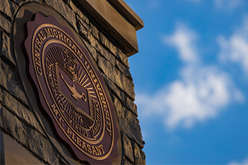 Round sign on a brick wall that reads Central Michigan University Mt. Pleasant.