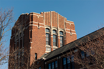 A tall brick building surrounded by trees.