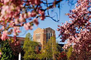 A brick building with flowering trees around it.