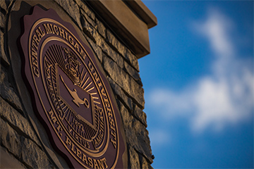 A round sign on a brick wall that says Central Michigan University.