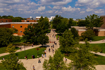 A view from above of people walking on sidewalks between large buildings.