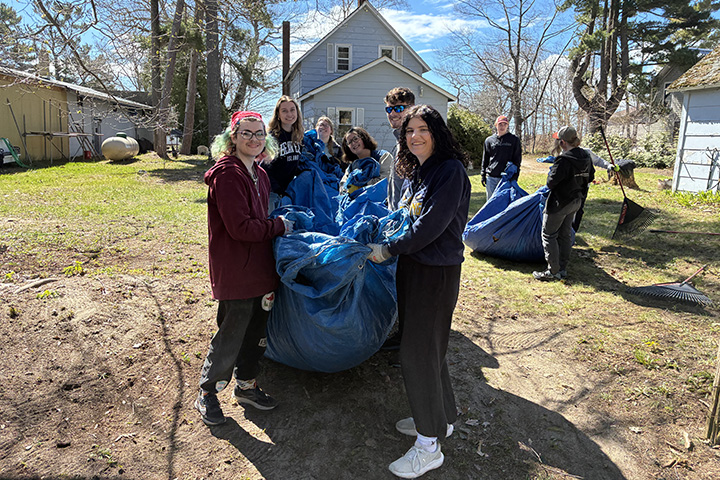 8 Honors students carry taps full of leaves in a backyard on Beaver Island
