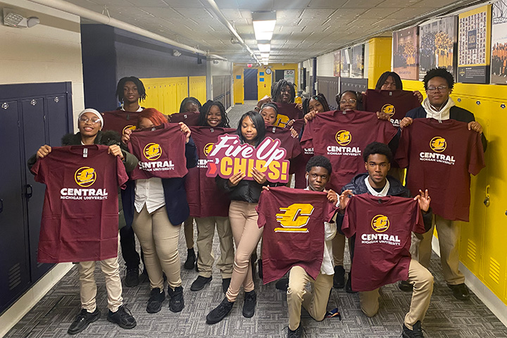 A group of high school students holding up CMU t-shirts