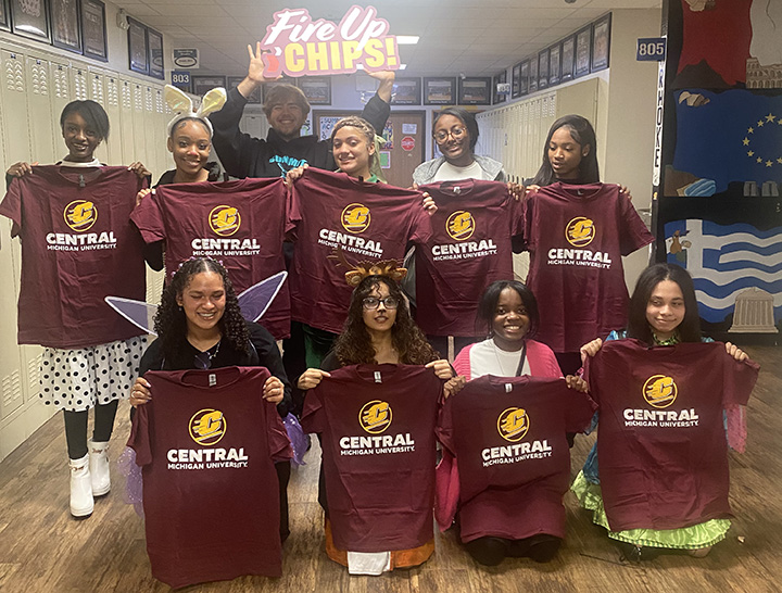 A group of high school students holding up CMU t-shirts