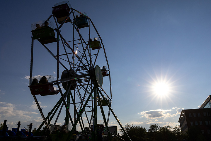 A ferris wheel is silouetted against a sunny sky