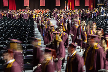 A blurred photo taken at a slow shutter speed of CMU graduates making their way to the stage