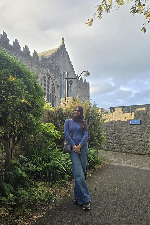A female student stands in front of a castle in Limerick, Ireland.