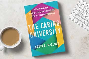 A copy of the book "The Caring University" sits next to a cup of coffee and a computer keyboard.