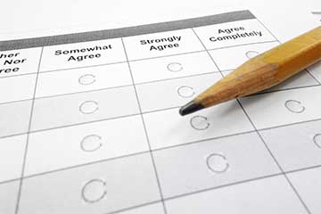 A sharpened yellow pencil sits on top of a grey and white survey document