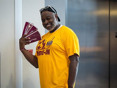 A smiling man holding maroon colored cards.