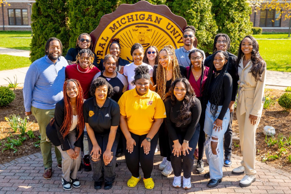 Group photo of students posing in front of the Central Michigan Seal