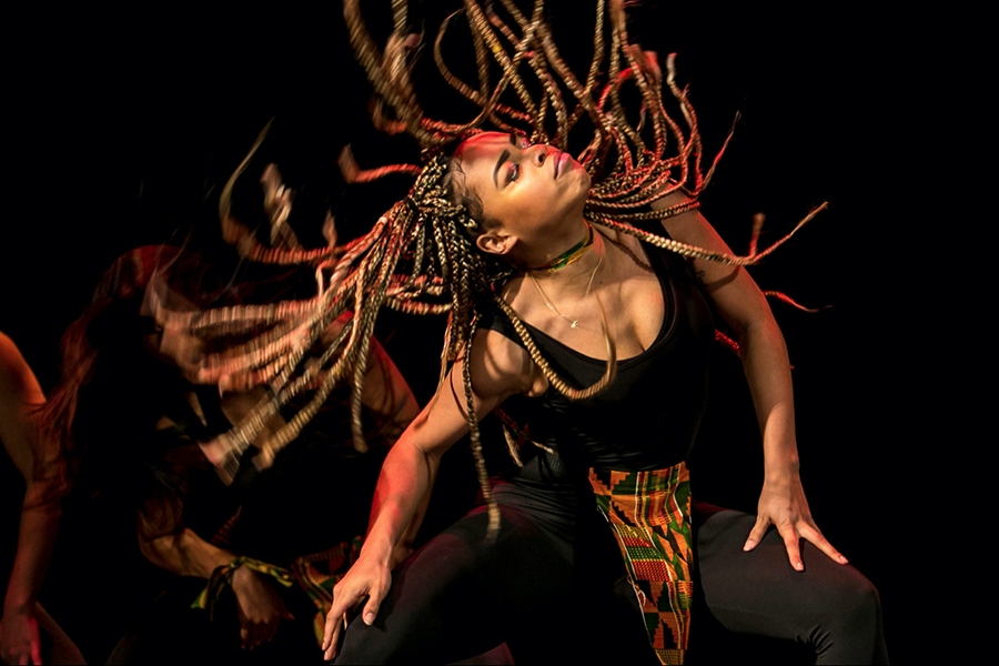 A Black female dancer swings braids to music